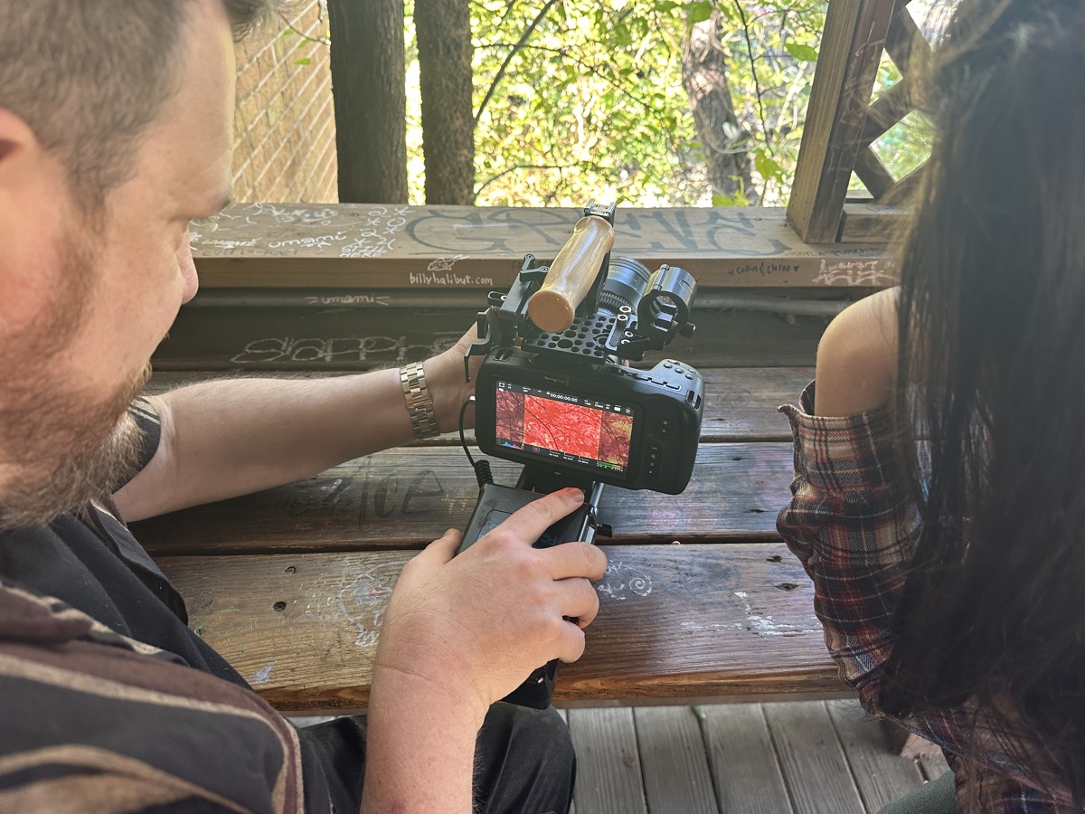 Crew member framing a shot with a rigged cinema camera